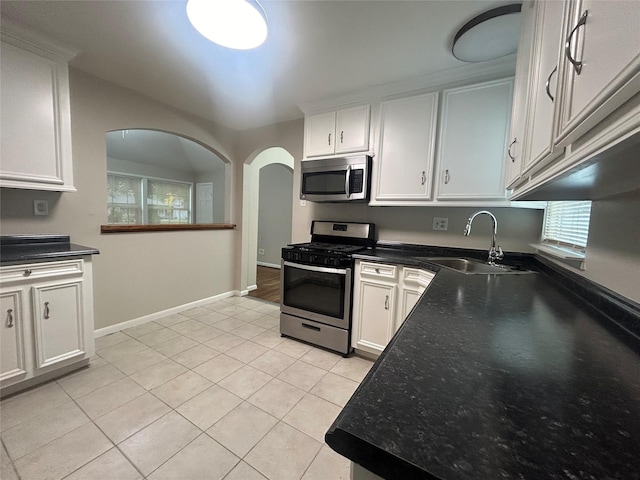 kitchen with baseboards, light tile patterned flooring, a sink, appliances with stainless steel finishes, and white cabinetry