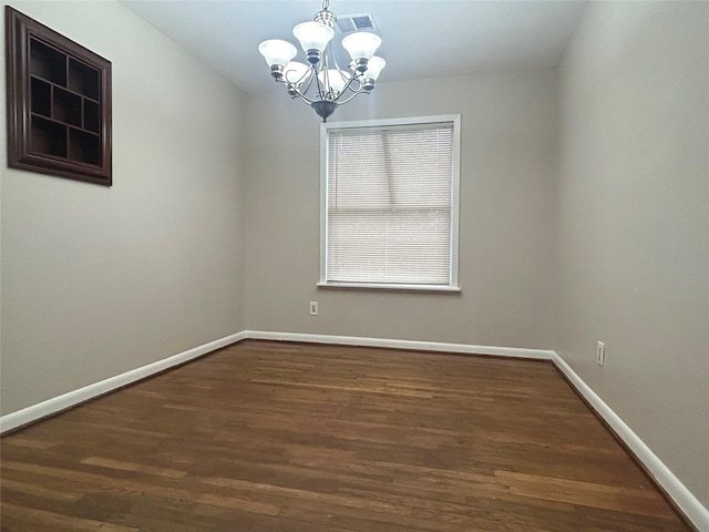 spare room with dark wood finished floors, visible vents, an inviting chandelier, and baseboards