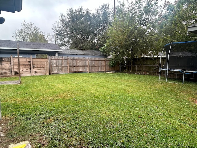 view of yard featuring a trampoline and a fenced backyard