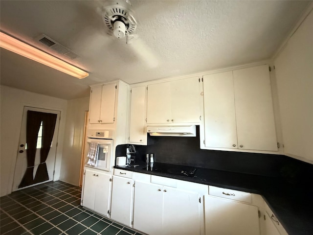 kitchen featuring visible vents, under cabinet range hood, dark countertops, white oven, and black electric stovetop