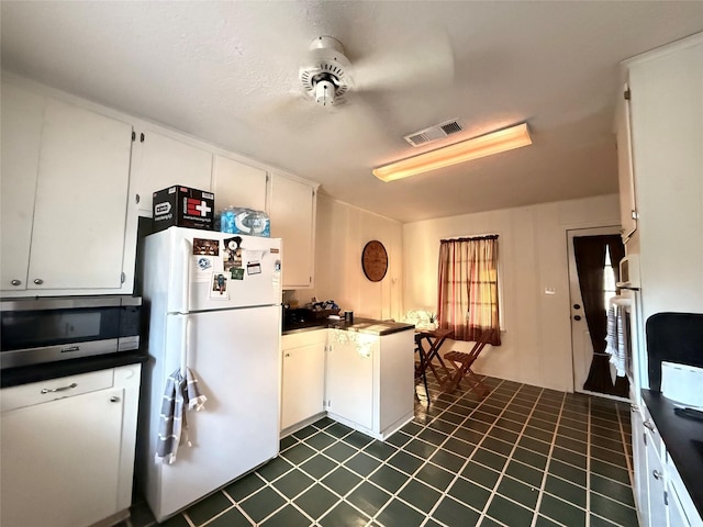 kitchen featuring dark countertops, visible vents, white appliances, and a peninsula