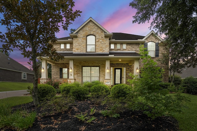 view of front of property featuring brick siding, stone siding, and covered porch