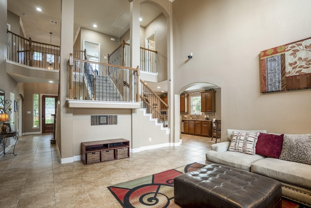 living area featuring baseboards, recessed lighting, arched walkways, stairs, and tile patterned floors