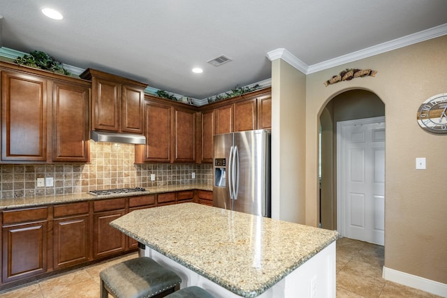 kitchen featuring tasteful backsplash, visible vents, under cabinet range hood, arched walkways, and stainless steel appliances