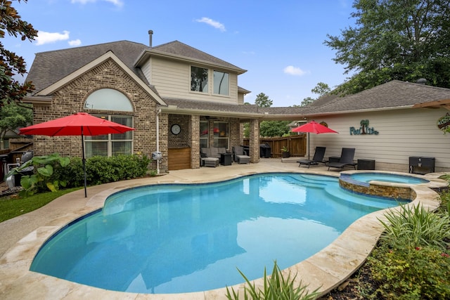 view of pool featuring fence, a pool with connected hot tub, and a patio area