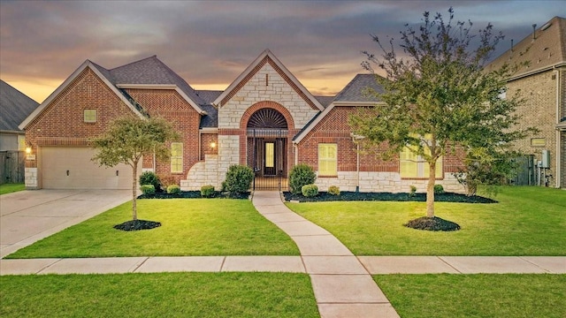 view of front of home featuring concrete driveway, a yard, brick siding, and stone siding