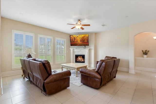 living room featuring visible vents, a ceiling fan, arched walkways, a fireplace, and baseboards