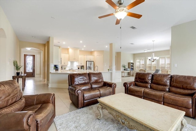 living room featuring visible vents, ceiling fan with notable chandelier, recessed lighting, arched walkways, and light tile patterned floors