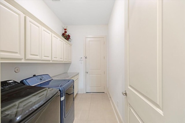 clothes washing area with light tile patterned floors, baseboards, cabinet space, and washing machine and clothes dryer