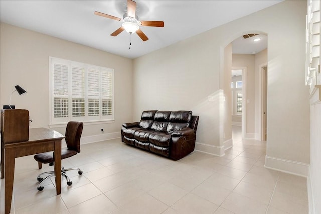 office featuring visible vents, baseboards, light tile patterned floors, arched walkways, and a ceiling fan