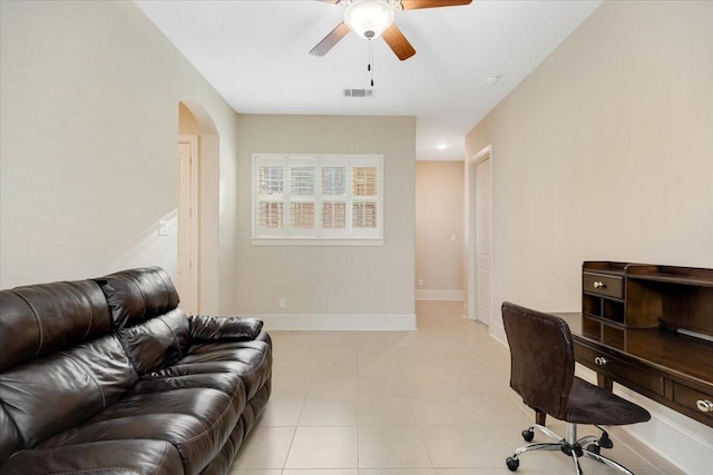 home office featuring visible vents, a ceiling fan, arched walkways, light tile patterned floors, and baseboards