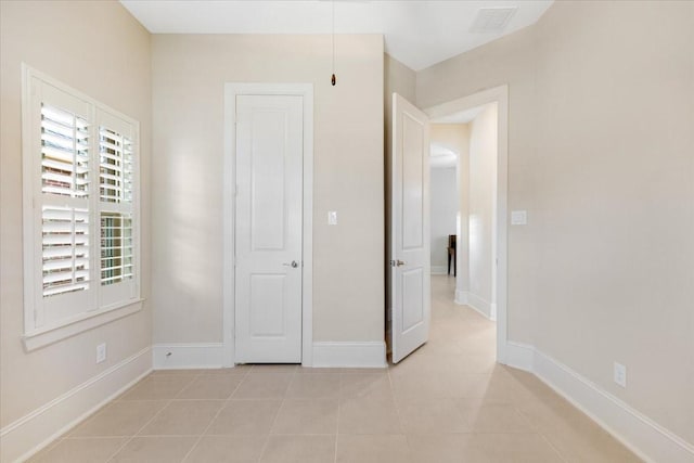 unfurnished bedroom featuring light tile patterned floors, visible vents, and baseboards