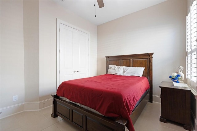 bedroom with light tile patterned floors, a closet, baseboards, and a ceiling fan