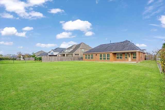 back of house featuring a lawn, a fenced backyard, and brick siding