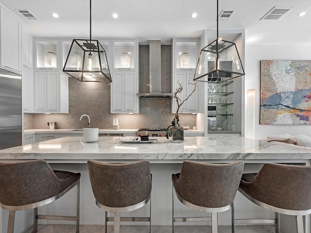 kitchen featuring visible vents, white cabinetry, and wall chimney exhaust hood