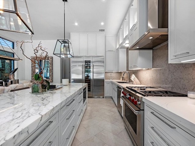 kitchen featuring visible vents, backsplash, wall chimney range hood, high quality appliances, and a sink