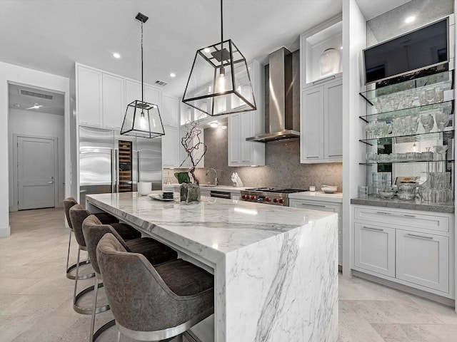 kitchen featuring tasteful backsplash, a kitchen island, wall chimney range hood, stainless steel built in refrigerator, and range