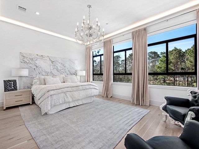 bedroom featuring light wood-type flooring, visible vents, multiple windows, and a chandelier