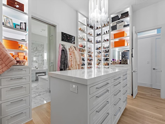 spacious closet with light wood-type flooring and a chandelier