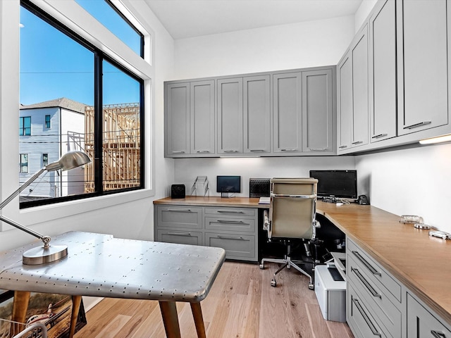 home office with light wood-style flooring and built in study area