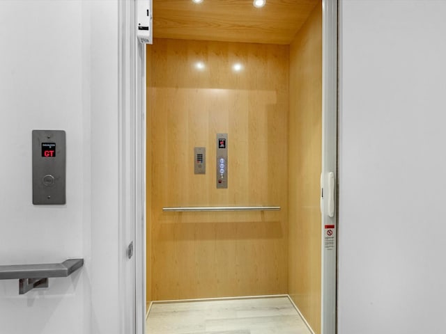 interior details with elevator, wood finished floors, and recessed lighting