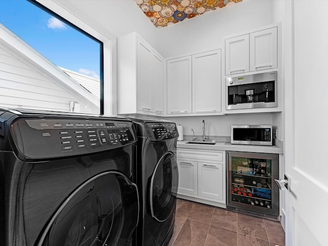 laundry area with beverage cooler, independent washer and dryer, cabinet space, and a sink