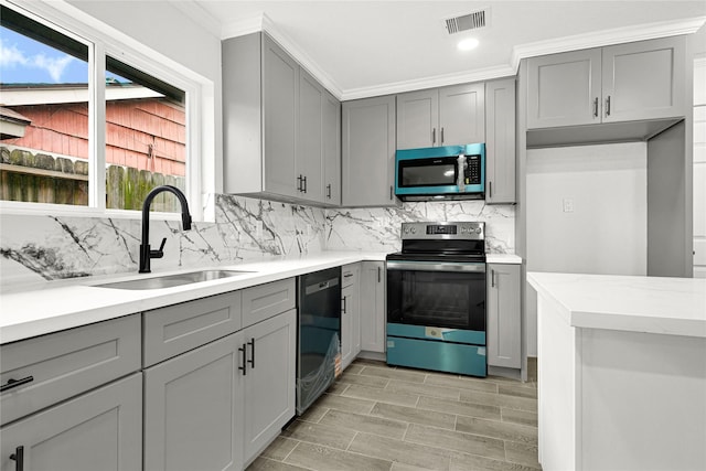 kitchen with visible vents, decorative backsplash, gray cabinets, stainless steel appliances, and a sink