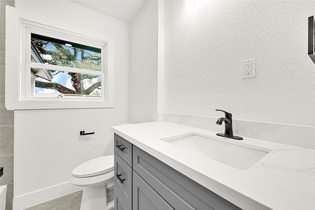 full bathroom with tile patterned flooring, baseboards, toilet, a textured wall, and vanity