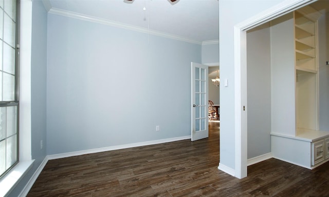 empty room featuring dark wood finished floors, crown molding, french doors, and baseboards