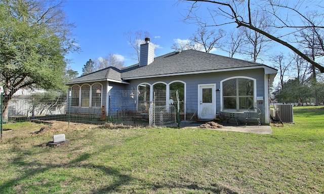 rear view of house with a patio, a yard, roof with shingles, central AC unit, and a chimney