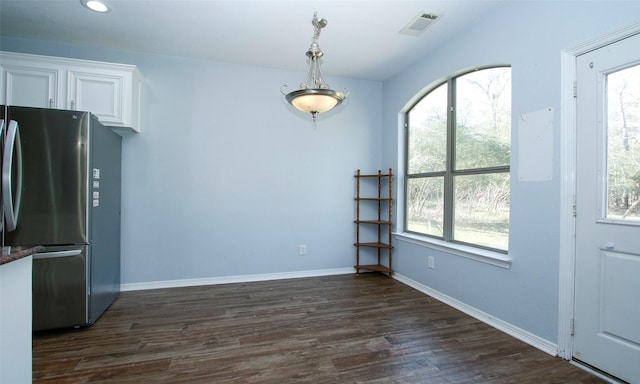 interior space featuring dark wood-style floors, visible vents, baseboards, freestanding refrigerator, and white cabinetry