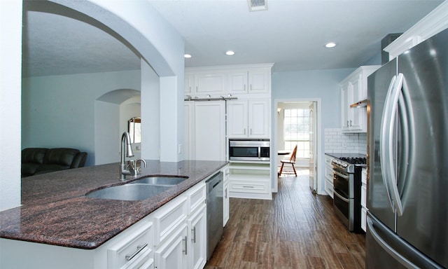 kitchen featuring tasteful backsplash, a sink, white cabinets, stainless steel appliances, and dark wood-style flooring