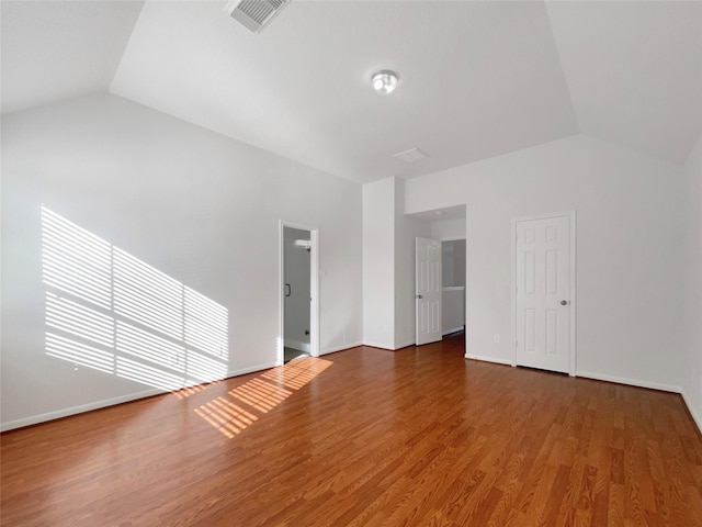 empty room featuring visible vents, baseboards, wood finished floors, and vaulted ceiling