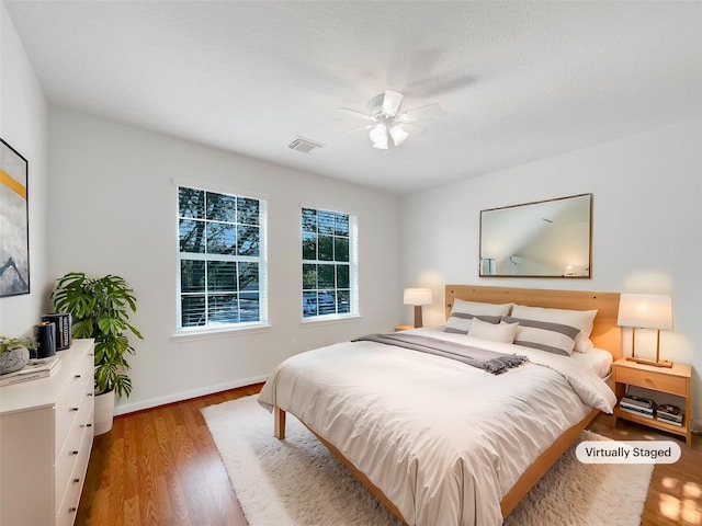 bedroom with visible vents, ceiling fan, baseboards, and wood finished floors