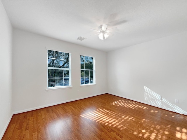 empty room with visible vents, baseboards, ceiling fan, and wood finished floors