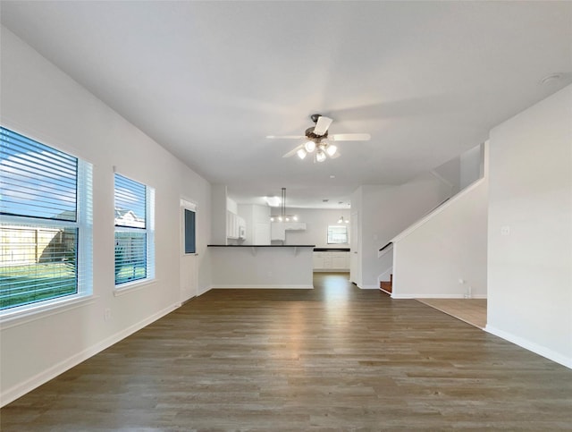 unfurnished living room with a ceiling fan, stairway, wood finished floors, and baseboards