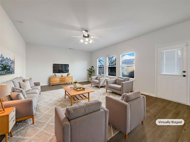 living room with ceiling fan, baseboards, and wood finished floors