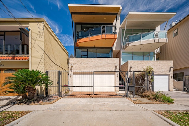 view of front of home with stucco siding, driveway, a gate, a fenced front yard, and a garage