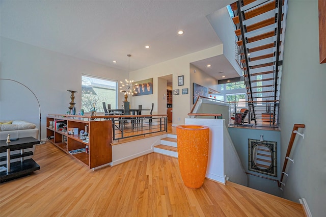 hallway with a chandelier, stairway, a healthy amount of sunlight, and wood finished floors