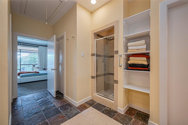 full bath with stone tile flooring, ensuite bathroom, baseboards, and a shower stall