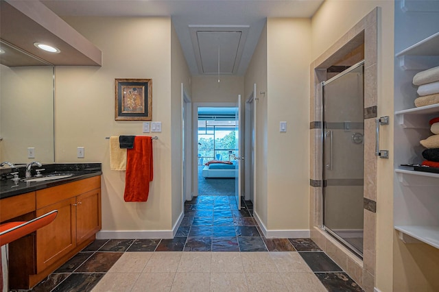 ensuite bathroom featuring baseboards, vanity, and a stall shower