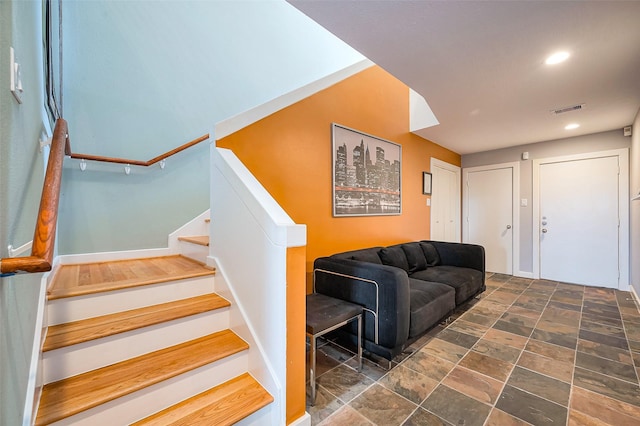 living room with recessed lighting, stone finish floor, stairway, and visible vents
