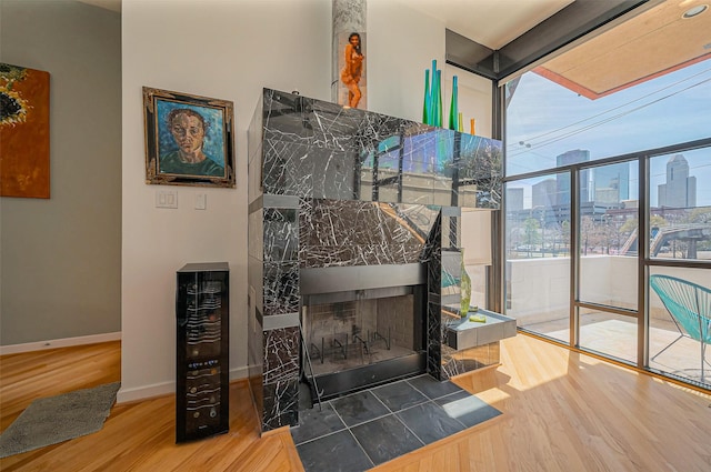 room details featuring baseboards, beverage cooler, a city view, a tile fireplace, and wood finished floors