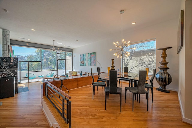 dining area featuring light wood-type flooring, baseboards, a notable chandelier, and a healthy amount of sunlight
