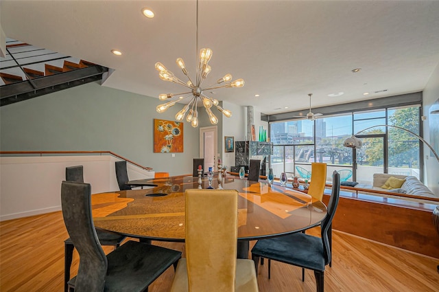 dining area featuring recessed lighting, wood finished floors, stairs, and ceiling fan with notable chandelier