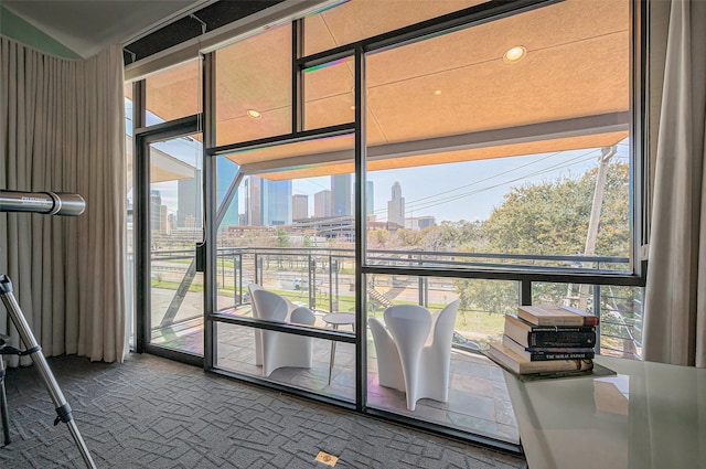 interior space featuring floor to ceiling windows, plenty of natural light, carpet flooring, and a view of city