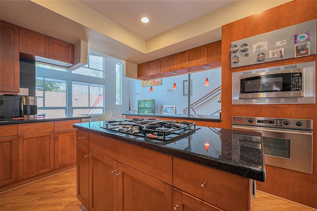 kitchen with brown cabinetry, appliances with stainless steel finishes, and light wood-type flooring