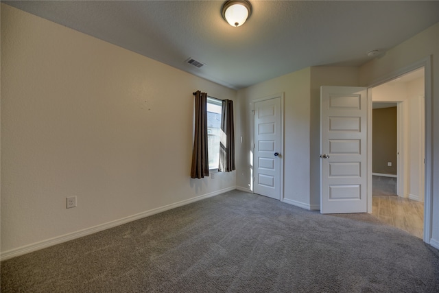 unfurnished bedroom featuring visible vents, dark colored carpet, and baseboards