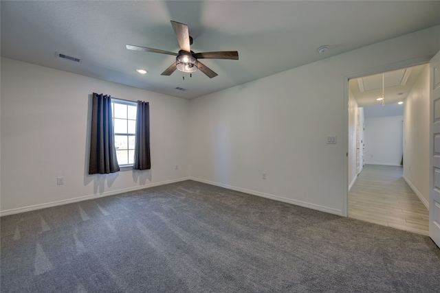 carpeted spare room featuring attic access, baseboards, and visible vents