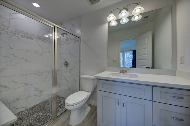 bathroom with visible vents, wood finish floors, toilet, a stall shower, and vanity